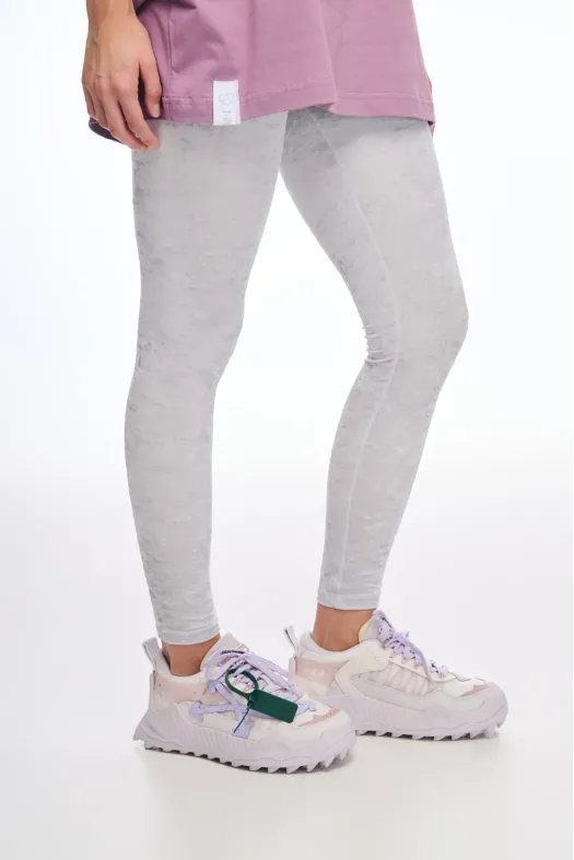 Person wearing gray leggings and white sneakers on a white background