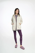 Woman wearing a cream hoodie and purple leggings on a white background