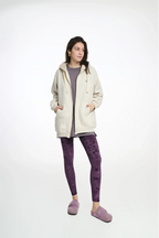 Person wearing a cream hoodie and purple leggings on a white background