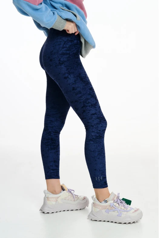 Person wearing blue patterned leggings and white sneakers on a white background
