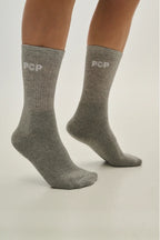 Gray socks with 'PCP' branding worn by a person on a light gray background