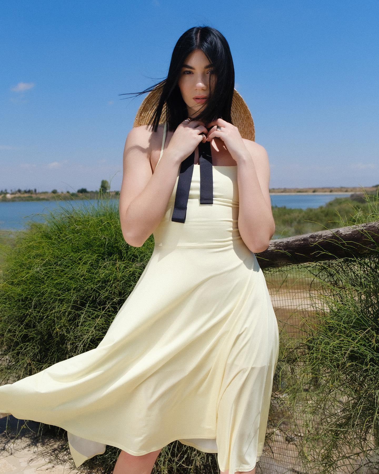 Woman in a yellow dress standing outdoors with a scenic background