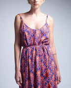 Woman wearing a blue and orange patterned dress against a gray background