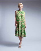 Woman wearing a green floral dress on a plain background