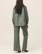 A person viewed from the back wearing green cargo pants with a button and zipper closure, and a matching green shirt.