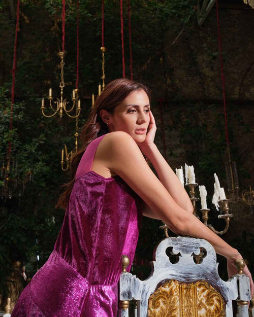 Woman in a purple dress sitting on an ornate chair with candles and chandeliers in the background