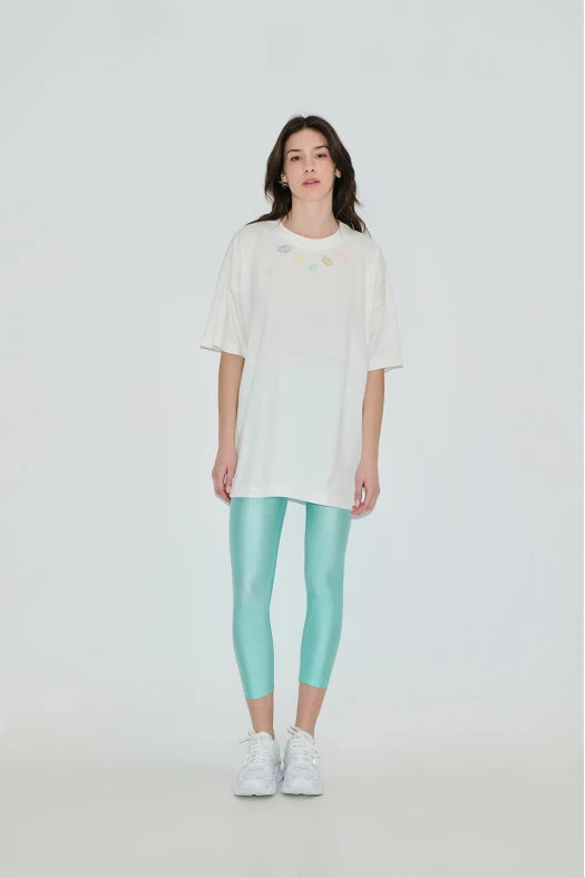 Person wearing a white oversized t-shirt and light blue leggings on a plain background