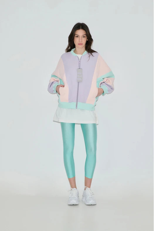 Person wearing a pastel-colored outfit with a jacket and leggings on a white background
