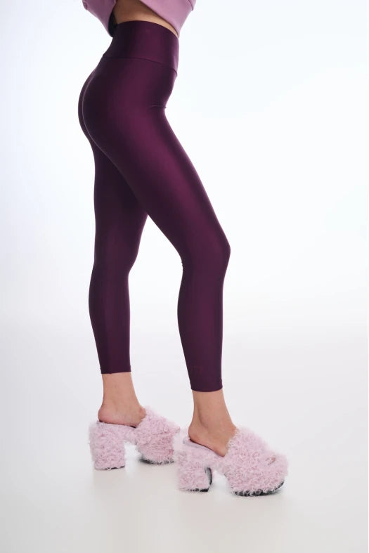 Person wearing maroon leggings and pink fuzzy shoes on a white background