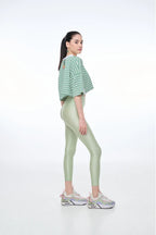 Woman wearing a green and white striped shirt and light green leggings on a white background