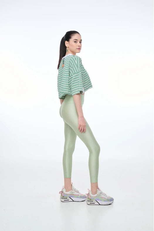 Woman wearing a green and white striped shirt and light green leggings on a white background