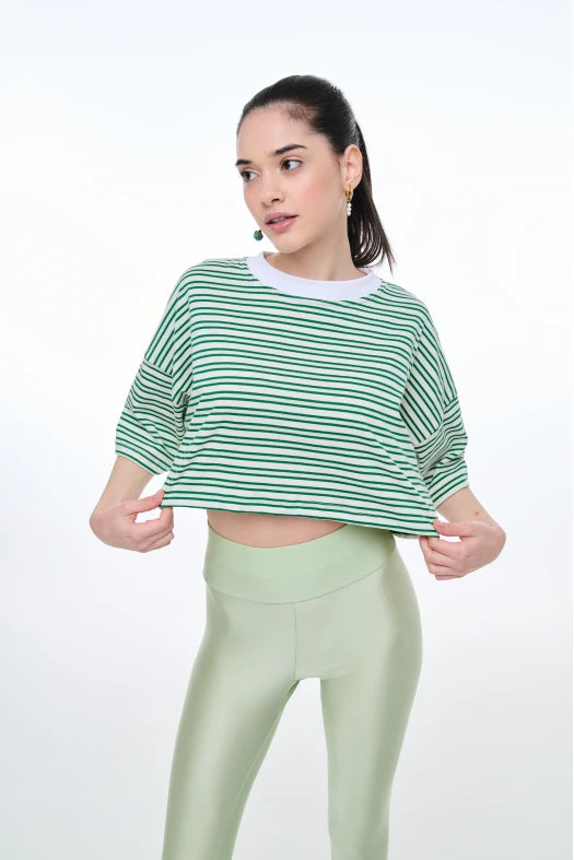 Woman wearing a green and white striped shirt and light green leggings on a white background