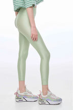 Person wearing light green leggings and colorful sneakers on a white background