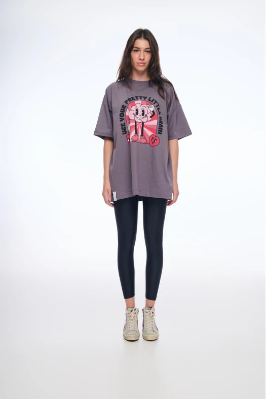 Woman wearing a gray oversized t-shirt with a graphic design on a white background