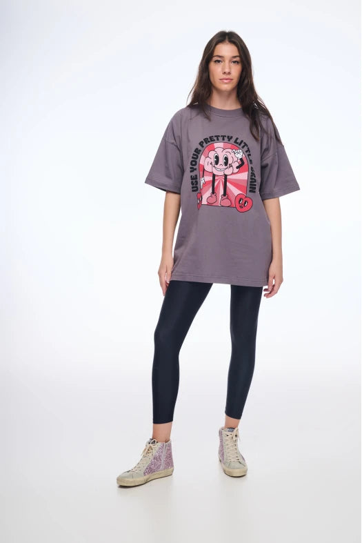 Person wearing a gray oversized t-shirt with a graphic design and black leggings on a white background