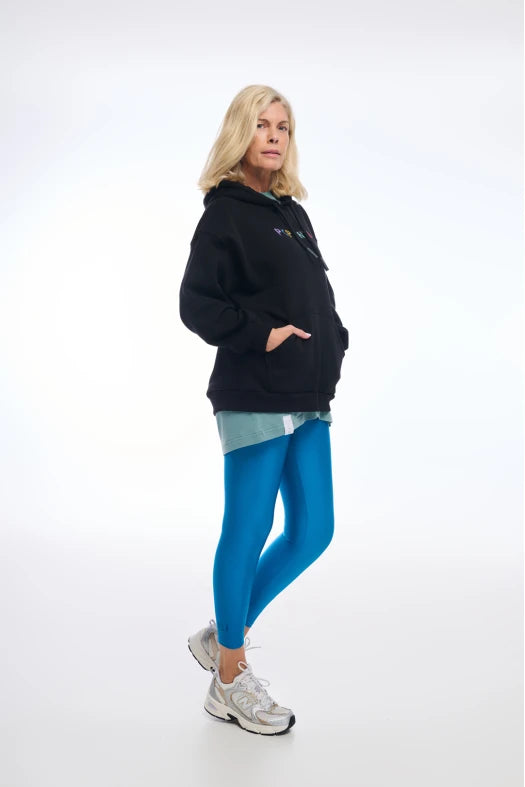 Woman wearing a black hoodie and blue leggings on a white background