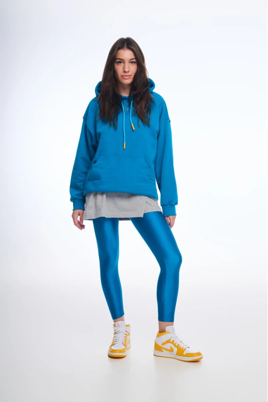 Woman wearing a blue hoodie and leggings with yellow sneakers on a white background