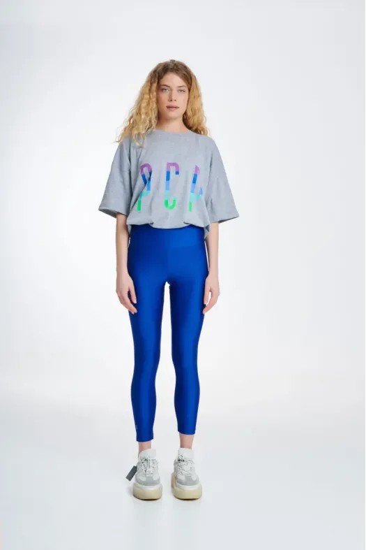 Person wearing a gray t-shirt with colorful text and blue leggings on a white background