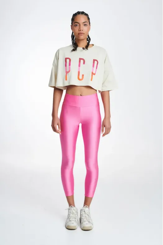 Woman wearing a white cropped top with colorful letters and pink leggings on a white background