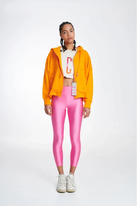 Person wearing a bright yellow hoodie, white crop top with red lettering, and pink leggings on a white background