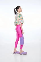 Person wearing a colorful jacket, pink leggings, and purple shoes on a white background