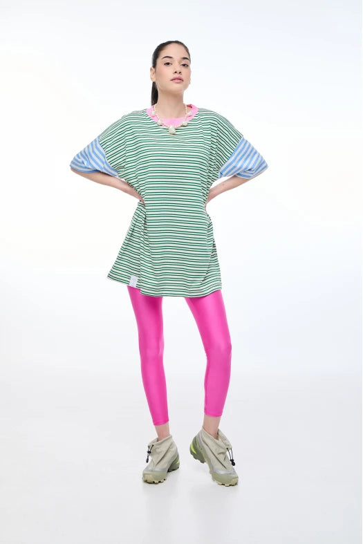 Person wearing a green and blue striped dress with pink leggings on a white background