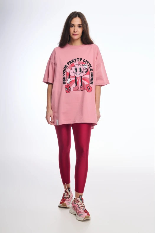 Person wearing a pink oversized t-shirt with a graphic design and red leggings on a white background