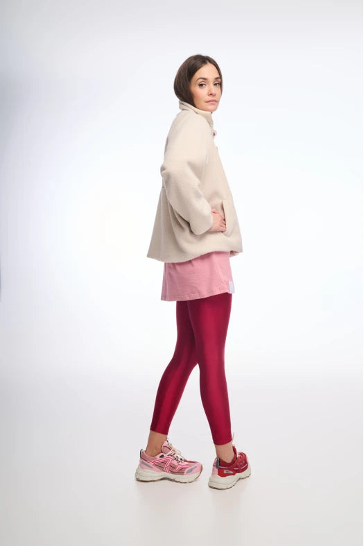 Person wearing a beige sweater, pink skirt, and red leggings on a white background