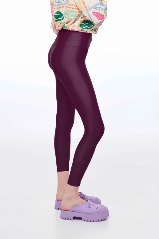 Person wearing purple leggings and matching shoes on a white background
