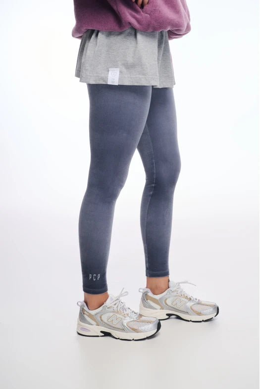 Person wearing gray leggings and white sneakers on a white background