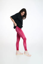 Woman wearing pink leggings and a black top on a white background