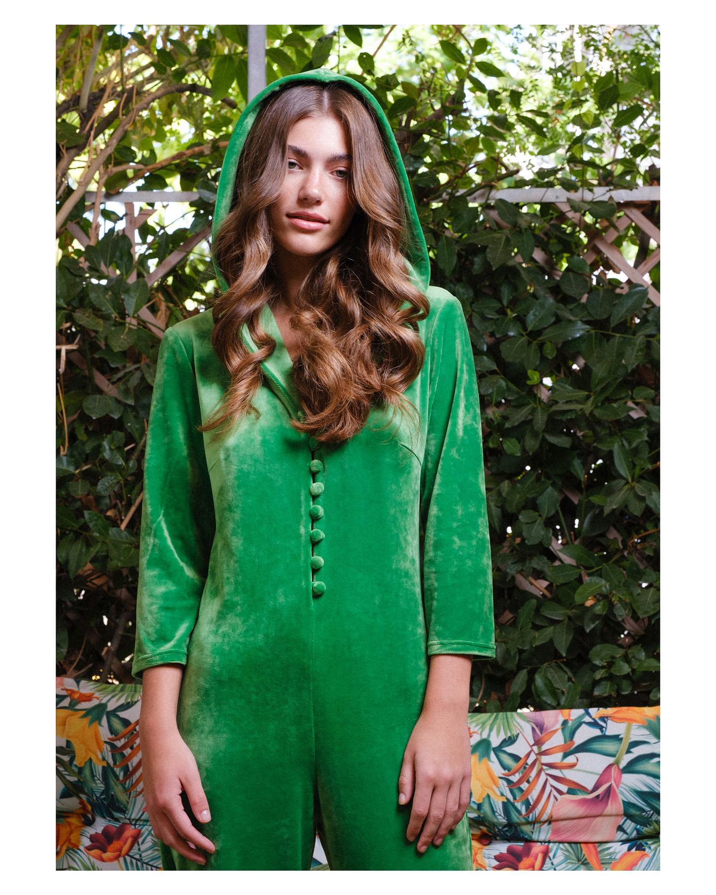 Person wearing a green hooded outfit with a leafy background