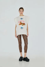 Person wearing a sleeveless graphic top and patterned leggings on a white background