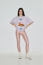 Person wearing a graphic t-shirt and patterned leggings on a white background