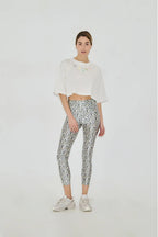 Woman wearing a white top and patterned leggings on a white background