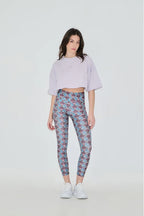 Woman wearing a light purple cropped top and patterned leggings on a white background