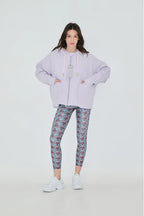 Person wearing a light purple hoodie and patterned leggings on a white background