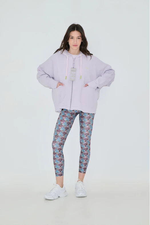 Person wearing a light purple hoodie and patterned leggings on a white background