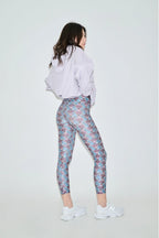 Woman wearing a white sweatshirt and patterned leggings on a white background