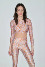 Woman wearing a patterned long-sleeve top and leggings set on a plain background