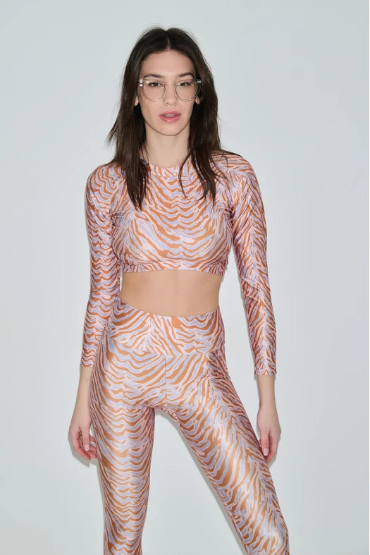 Woman wearing a patterned long-sleeve top and leggings set on a plain background