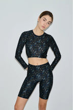 Woman wearing a black floral athletic outfit on a light gray background
