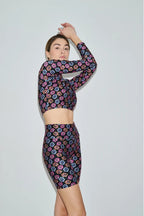 Woman wearing a colorful floral dress against a plain background