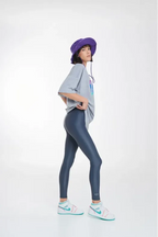 Person wearing a gray t-shirt, blue leggings, and a purple hat on a white background