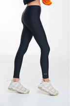 Person wearing black leggings and white sneakers on a white background