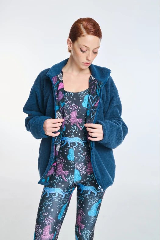 Woman wearing a blue fleece jacket and patterned pajama set on a white background