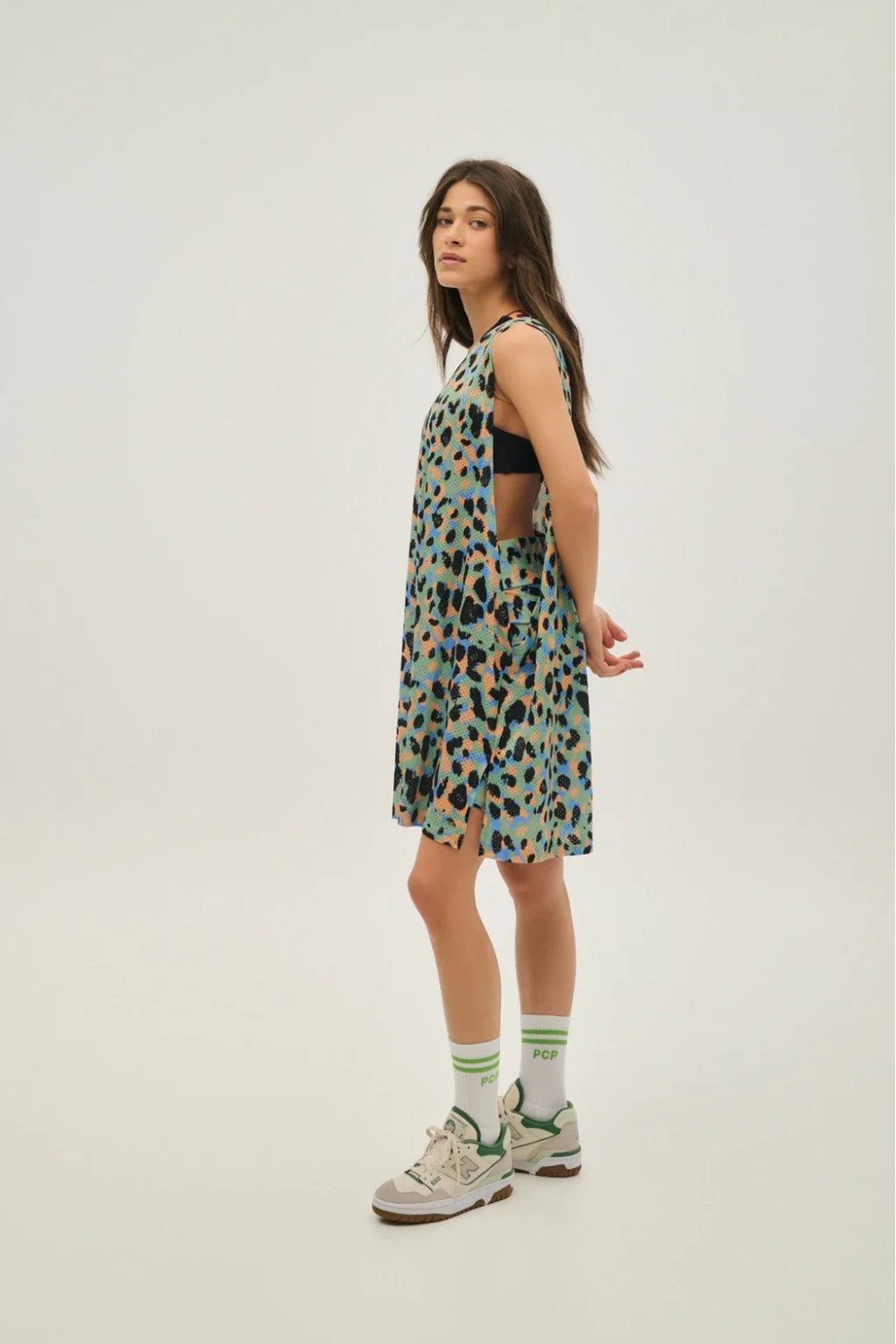 Woman wearing a patterned dress and sneakers on a white background