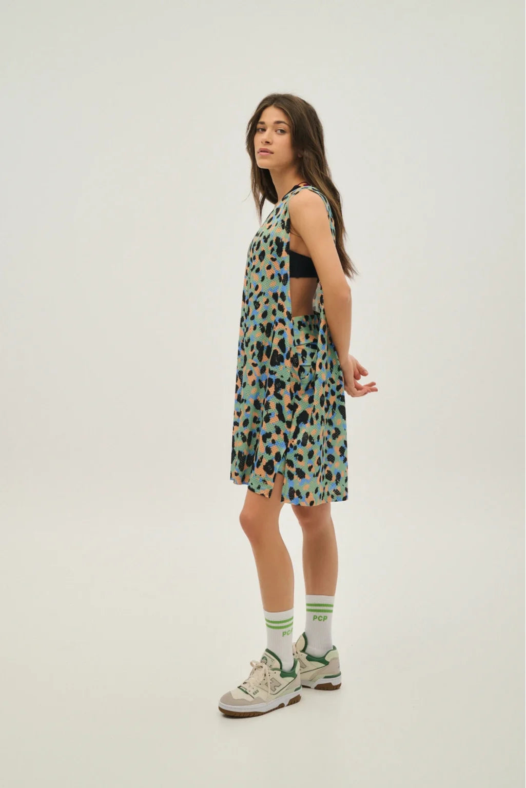Woman wearing a patterned dress and sneakers on a white background