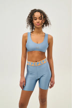 Woman wearing a blue sports bra and shorts set with a white background