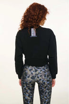 Person wearing a black sweatshirt and camouflage pants on a white background